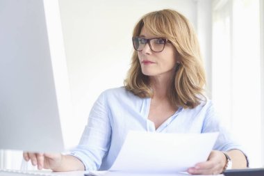 Ofis Masası oturma ve bilgisayarda çalışarak işkadını yakın çekim portre emin orta yaşlı. 