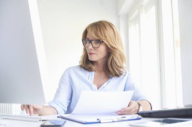 Ofis Masası oturma ve bilgisayarda çalışarak işkadını yakın çekim portre emin orta yaşlı. 