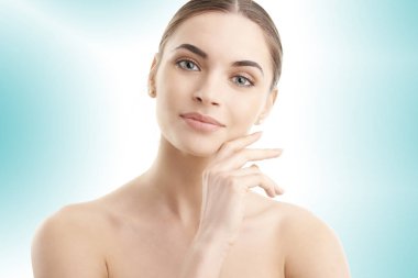 Stüdyo çekim güzel gülümseyen kadın yüzünü dokunaklı ve kameraya bakarak kırpılmış. Açık mavi renkli izole. 