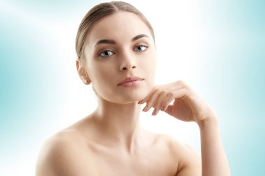 Stüdyo çekim güzel gülümseyen kadın yüzünü dokunaklı ve kameraya bakarak kırpılmış. Açık mavi renkli izole. 