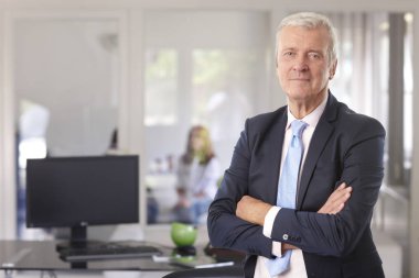 A senior financial advisor businessman standing with arms crossed at the office. clipart