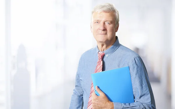Portrait of a senior financial consultant standing holding document in his hand while standing at the office.