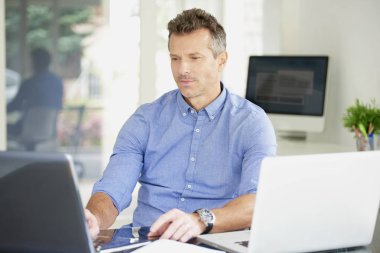 Ofiste iş istasyonunda çalışırken dizüstü kullanarak düşünme rahat bir iş adamı. Çoklu görev. 