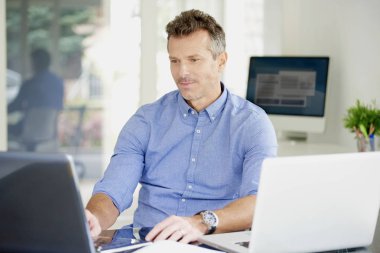 Ofiste iş istasyonunda çalışırken dizüstü kullanarak düşünme rahat bir iş adamı. Çoklu görev. 