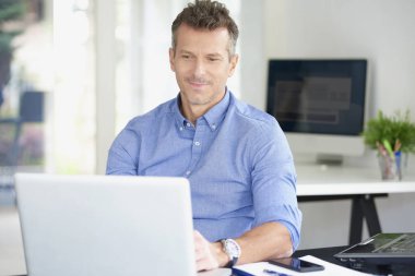 Ofis Masası oturma ve onun bilgisayar kullanarak forması giyen işadamı orta yaşlı. 