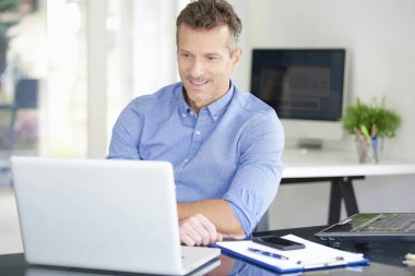 Ofis Masası oturma ve onun bilgisayar kullanarak forması giyen işadamı orta yaşlı. 