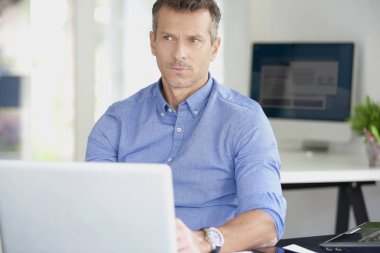 Ofis Masası oturma ve onun bilgisayar kullanarak forması giyen işadamı orta yaşlı. 