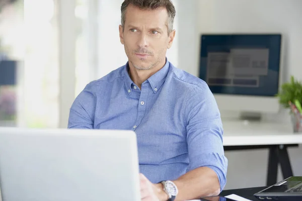 中年ビジネスマンのオフィスの机に座っていると 彼のコンピューターを使用している間のシャツを着て — ストック写真