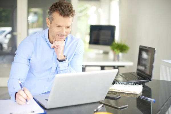 Financial consultant businessman looking thoughtfully while sitting in front of laptop and calculating financial data.