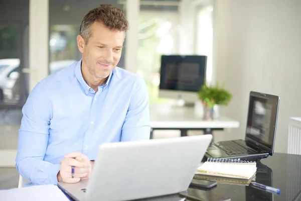 笑顔の営業ビジネスマン彼のラップトップを使用してオフィスでオンラインのショット — ストック写真