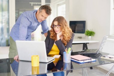 Onun yanında duran ve finansal veriler hakkında danışmanlık satış işadamı emin işkadını onu laptop orta kullanarak çekim yaşlı. 