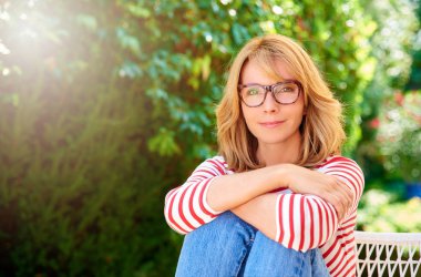 Güzel gülümseyen orta yaşlı kadının açık ve rahatlatıcı bahçede oturan kırpılmış atış. 