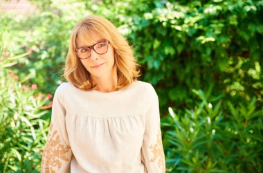 Güzel orta yaşlı kadının açık ayakta iken gülümsüyor atış kırpılmış. 