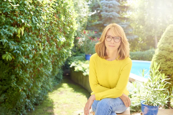 高角度拍摄美丽的女人穿着毛衣和牛仔裤 而坐在花园和放松 — 图库照片