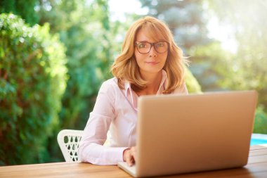 Çekici gülümseyen kadın bahçede evde otururken onu laptop kullanma. 