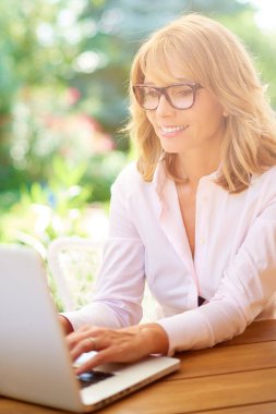 Yüksek açı portre çekici kadın dışında çalışırken dizüstü bilgisayar kullanarak bir kadeh. Ev ofis. 