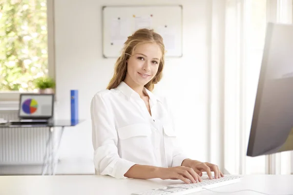 Όμορφη Νεαρή Επιχειρηματίας Πληκτρολογώντας Στο Πληκτρολόγιο Ενώ Κάθεται Στο Γραφείο — Φωτογραφία Αρχείου