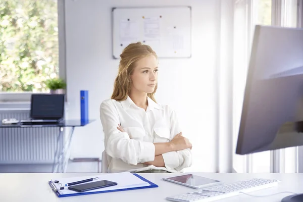 年轻漂亮的女商人坐在办公桌前 在计算机上工作时思考新项目 — 图库照片