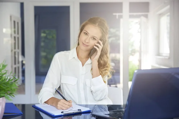 美しい若いアシスタントの机に座って ノートを作成しながら実業家呼び出しの肖像画 — ストック写真
