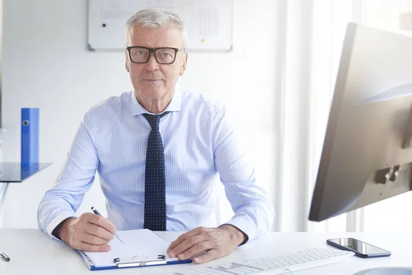 Shot of financial professional man doing some paperwork while sitting at office desk.