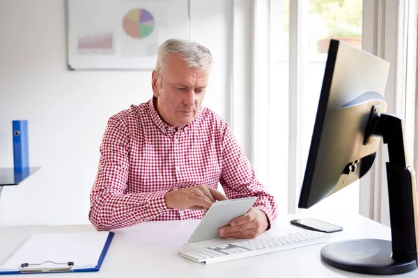 Ανώτερος Επιχειρηματίας Χρησιμοποιώντας Ψηφιακή Δισκίο Του Ενώ Κάθεται Στο Γραφείο — Φωτογραφία Αρχείου