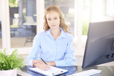 Ofis masası, laptop önünde oturma sırasında Notlar yapma güzel genç kadın. 