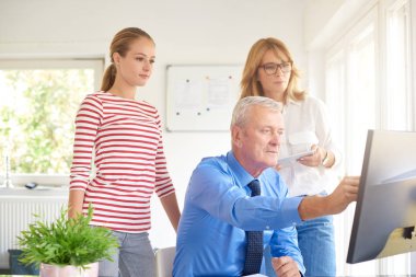 İş arkadaşları yeni mali rapor üzerinde çalışırken konuşuyor. Bilgisayar başında oturan ve bir şey iş arkadaşları için gösterilen üst düzey mali danışmanı. Ofiste takım çalışması. 