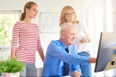 İş arkadaşları yeni mali rapor üzerinde çalışırken konuşuyor. Bilgisayar başında oturan ve bir şey iş arkadaşları için gösterilen üst düzey mali danışmanı. Ofiste takım çalışması. 