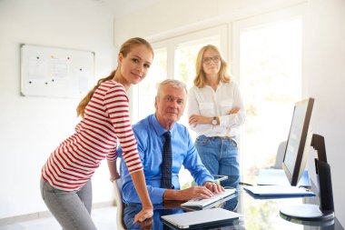 Bilgisayar başında oturan ve arkadaşları ile konuşmak kıdemli Finans Müdürü iş adamı vurdu. Ofiste takım çalışması. 