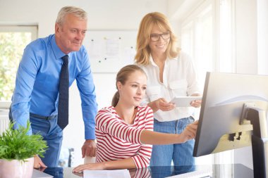 Bilgisayar başında oturan ve onun meslektaşları ile danışmanlık genç mali asistanı iş kadını. Ofiste takım çalışması. 