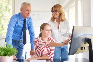 Bilgisayar başında oturan ve onun meslektaşları ile danışmanlık genç mali asistanı iş kadını. Ofiste takım çalışması. 