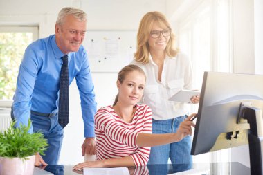 Bilgisayar başında oturan ve onun meslektaşları ile danışmanlık genç mali asistanı iş kadını. Ofiste takım çalışması. 