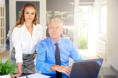 Üst düzey yönetici işadamı onun yanındaduruyor ve birlikte beyin fırtınası genç mali asistanı işkadını iken dizüstü bilgisayar önünde oturup bir kadeh. Ekip çalışması iinthe ofis.