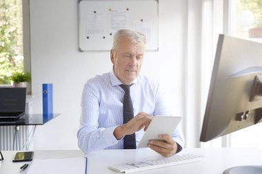 Ofiste çalışırken dijital tablet kullanarak üst düzey iş adamı vurdu. 