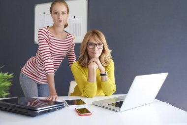 Orta doz iş kadını ve birlikte yeni proje üzerinde çalışırken dizüstü kullanarak onun genç asistanı yaşında. Ofiste takım çalışması.