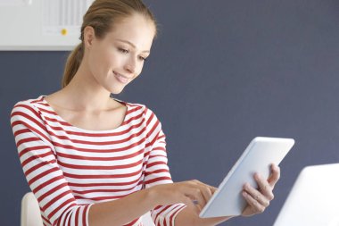 Ofis masa başında oturan ve onun e-posta kontrol ederken dijital tablet kullanarak rahat genç işkadını portresi.