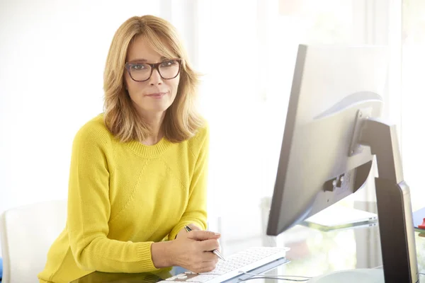 有吸引力的微笑女实业家的肖像坐在笔记本电脑前 看着相机 同时在电脑上工作 — 图库照片