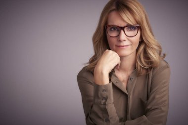 Gülümseyen kendine güvenen kadın kameraya ise açık gri renkli önünde oturma seyir stüdyo çekim. 