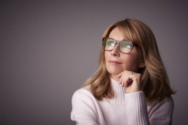 Orta düşünme Clos-up stüdyo portre gri bacgkround kopya alanı ile oturan kadın yaşlı. 