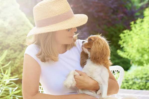 キャバリア Kingcharles 子犬犬と庭に座っている麦わら帽子身に着けている女性のショット — ストック写真