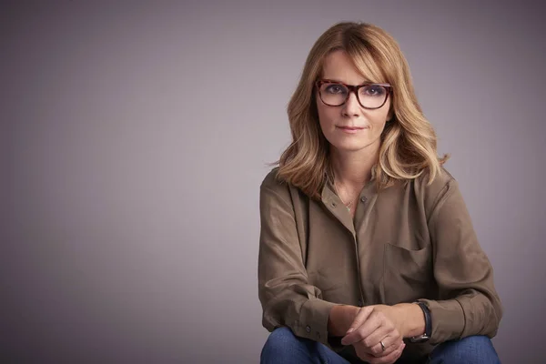 Retrato Estudio Una Atractiva Mujer Mediana Edad Sentada Frente Fondo —  Fotos de Stock