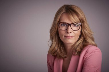 Gülümseyen yakın çekim studio portresi ve ceket gri arka plan otururken giyen kendine güvenen kadın. 