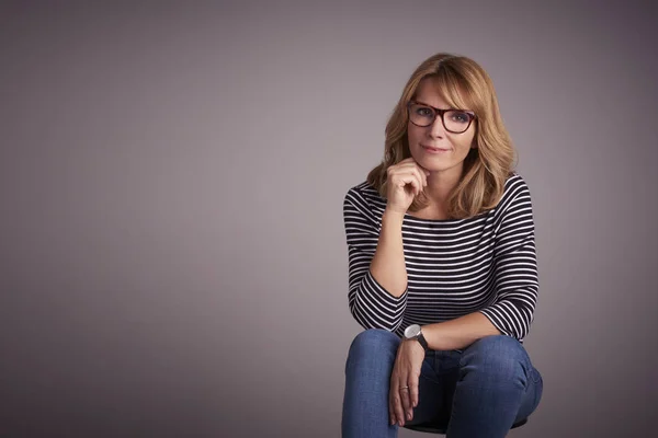 Studio Portret Van Een Aantrekkelijke Vrouw Zitten Tegen Grijze Achtergrond — Stockfoto