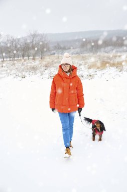 Mutlu kadın ile onun küçük köpek kar yağışı açık yürüyüş doz tam uzunlukta.