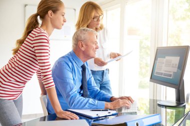 Bilgisayar başında oturan ve arkadaşları ile konuşmak kıdemli Finans Müdürü iş adamı vurdu. Ofiste takım çalışması. 