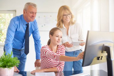 Bilgisayar başında oturan ve onun meslektaşları ile danışmanlık genç mali asistanı iş kadını. Ofiste takım çalışması. 