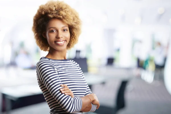 A laughing young sales assistant businesswoman standing with arms crossed at the office.