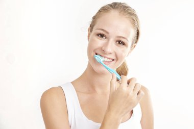 Kameraya bakarak ve gülümseyen dişlerini fırçalama güzel genç kadının Studio vurdu. Beyaz arka plan üzerinde izole.