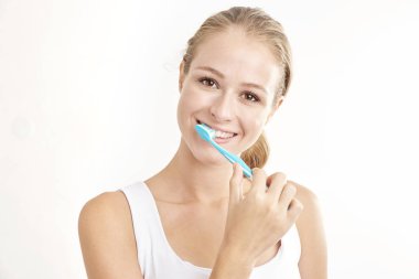 Kameraya bakarak ve gülümseyen dişlerini fırçalama güzel genç kadının Studio vurdu. Beyaz arka plan üzerinde izole.