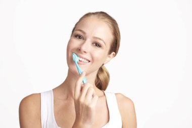 Kameraya bakarak ve gülümseyen dişlerini fırçalama güzel genç kadının Studio vurdu. Beyaz arka plan üzerinde izole. 